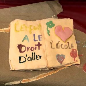 Photographie d'un livre peint par un enfant avec le message 'L'enfant a le droit d'aller à l'école', illustrant les services de médiation familiale et de défense des droits de l'enfant à la Maison Caracol.